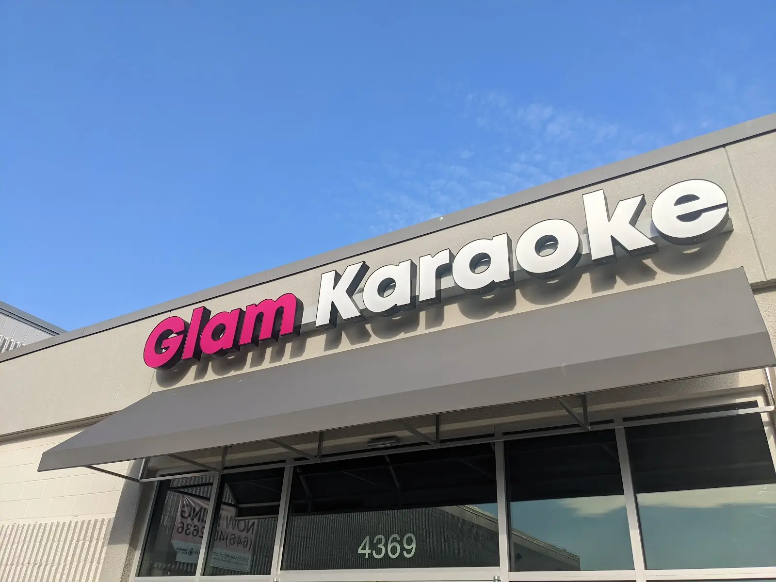 Glam Karaoke storefront sign against blue sky in Annandale, VA